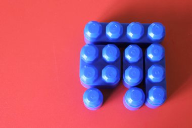 Kırmızı bir zemin üzerine oynamak, inşa etmek ve organize etmek için renkli plastik bloklar eklenebilir, çeşitlilik ve çoğulculuk kavramı bir üyeden yoksundur, tamamlanacak bir parça