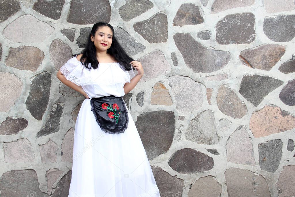 Young woman from Veracruz proudly and happily wears a traditional regional Mexican white dress with bare shoulders and black apron as part of the culture, dance and roots of Mexico