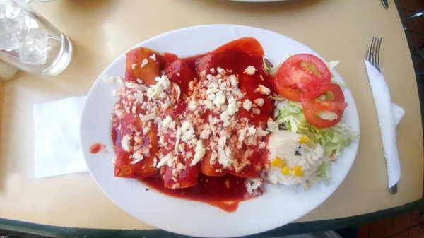 Typical Mexican dish Red Zacatecan Enchiladas for breakfast, lunch or dinner tradition and pride of the Mexican state made with corn tortilla, pork with cheese and salad
