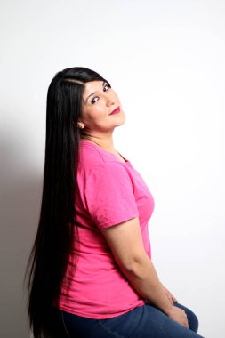 Latin yetişkin kadın kameraya poz veriyor. Uzun düz siyah saçları, sağlıklı, parlak ve ipeksi saçlarını gösteriyor. Mutlu ve heyecanlı görünüyor.