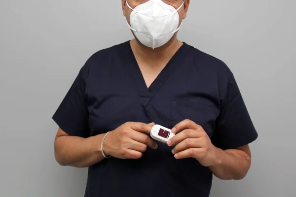 身穿蓝色制服 戴着面罩的男人 他的手上的手指显示了如何使用血氧计来测量怀疑患有Covid 19型糖尿病的病人的脉搏和氧合 — 图库照片