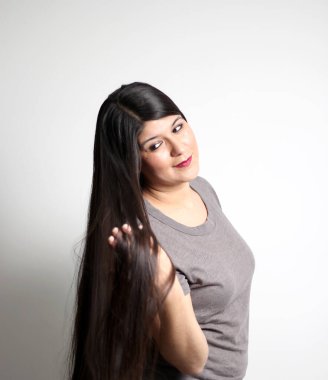 Şişman Latin yetişkin kadın, siyah saçlarının ne kadar ipeksi ve parlak olduğunu gösteriyor. Çok uzun, düz. Bunu eline alıyor, çok mutlu ve güzel saçlarıyla gurur duyuyor.