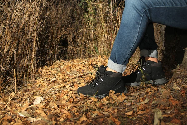 デニムパンツと黒いハイキングブーツを履いた女性の足だけで森の中を歩くの社会問題の一部と誘拐 レイプ 暗闇の中で女性の行方不明犠牲者 — ストック写真