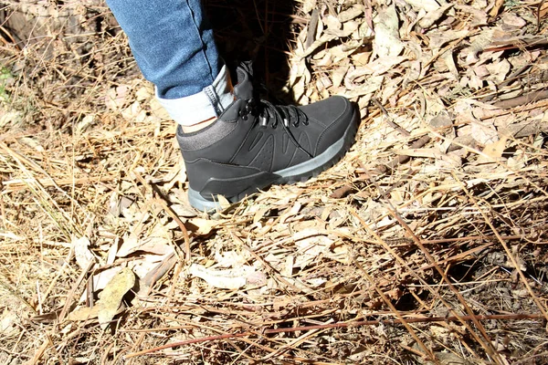 一名穿着牛仔裤和黑色徒步靴的妇女的腿在森林中独自行走 这是失踪和在黑暗中被绑架 强奸和杀害妇女的下落不明的社会问题的一部分 — 图库照片