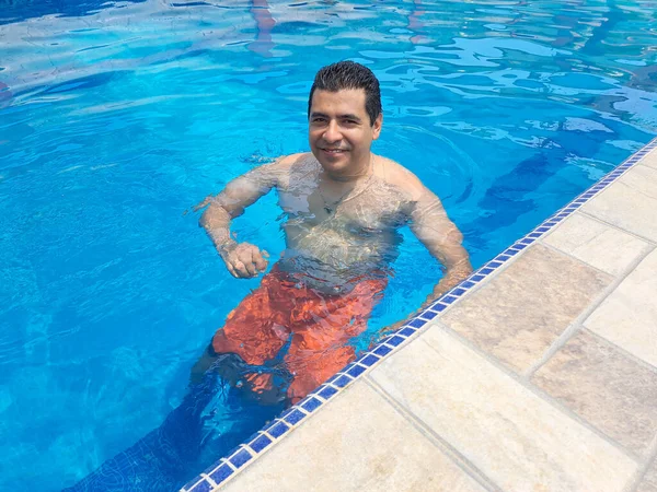 夏休みや週末にプールで泳ぐラテン系の成人男性は 日焼け止めを皮膚保護剤として使用しています — ストック写真