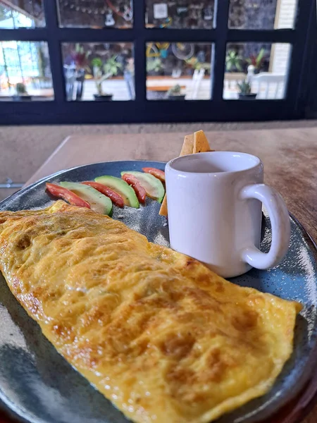 Meksika usulü omlet kahvaltısı, mantarla doldurulmuş avokado, domates, kırmızı sos, peynirli fasulye ve ahşap bir masanın yanındaki pencerenin yanında tortilla cipsi.