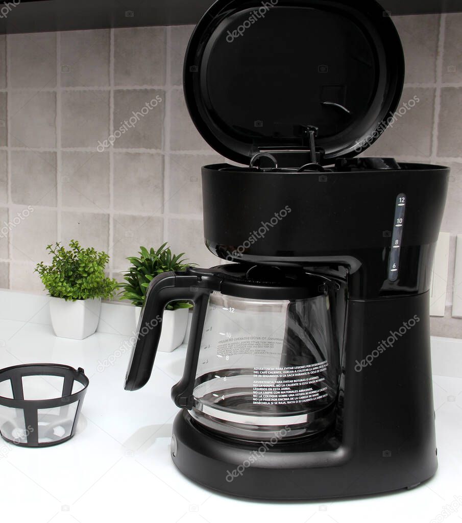 Black coffee maker to prepare American coffee with glass jug with reusable filter to put ground coffee and obtain the infusion preparing breakfast in the kitchen