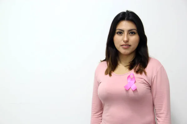 latin woman with pink blouse and pink ribbon for campaign against breast cancer on white background