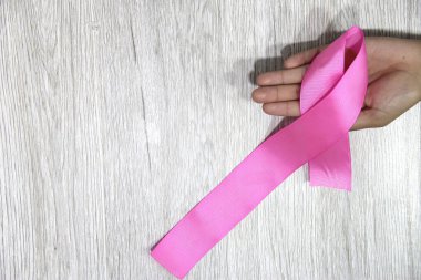Kadın elleri ve göğüs kanserine karşı kampanya için klasik gri ahşap arka planda pembe kurdele