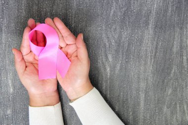 Kadın elleri ve göğüs kanserine karşı kampanya için klasik gri ahşap arka planda pembe kurdele