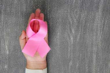 Kadın elleri ve göğüs kanserine karşı kampanya için klasik gri ahşap arka planda pembe kurdele
