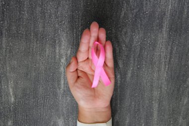 Kadın elleri ve göğüs kanserine karşı kampanya için klasik gri ahşap arka planda pembe kurdele