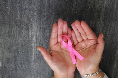 Kadın elleri ve göğüs kanserine karşı kampanya için klasik gri ahşap arka planda pembe kurdele