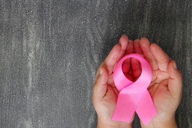 Kadın elleri ve göğüs kanserine karşı kampanya için klasik gri ahşap arka planda pembe kurdele