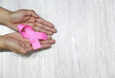 Kadın elleri ve göğüs kanserine karşı kampanya için klasik gri ahşap arka planda pembe kurdele