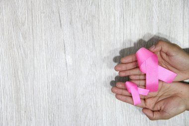 Kadın elleri ve göğüs kanserine karşı kampanya için klasik gri ahşap arka planda pembe kurdele