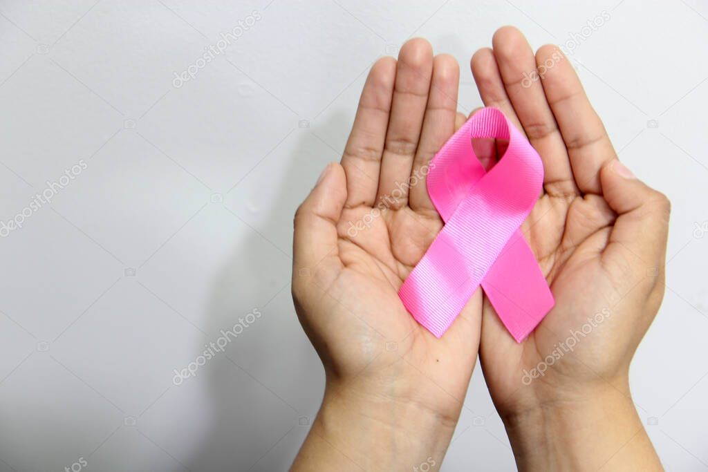 Female hands and pink ribbon on white background for campaign against breast cancer