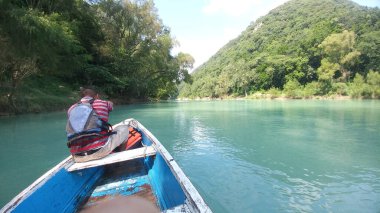 Güneş yanığı siyah saçlı Latin bir adam, San Luis Potosi Meksika 'daki Aquismon Şelalesi' ndeki berrak göl üzerinde kürek çekiyor.