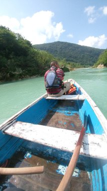 Güneş yanığı siyah saçlı Latin bir adam, San Luis Potosi Meksika 'daki Aquismon Şelalesi' ndeki berrak göl üzerinde kürek çekiyor.