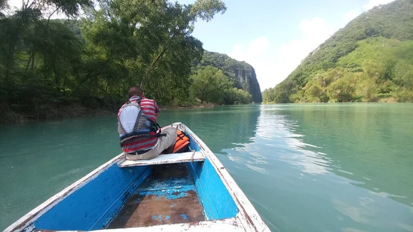 Güneş yanığı siyah saçlı Latin bir adam, San Luis Potosi Meksika 'daki Aquismon Şelalesi' ndeki berrak göl üzerinde kürek çekiyor.