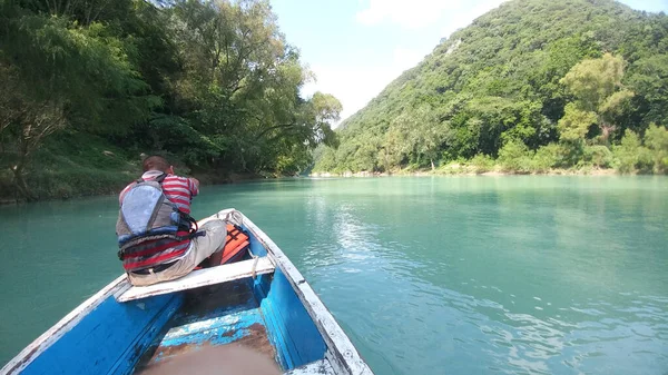 Güneş yanığı siyah saçlı Latin bir adam, San Luis Potosi Meksika 'daki Aquismon Şelalesi' ndeki berrak göl üzerinde kürek çekiyor.