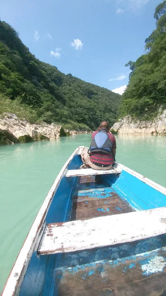 Güneş yanığı siyah saçlı Latin bir adam, San Luis Potosi Meksika 'daki Aquismon Şelalesi' ndeki berrak göl üzerinde kürek çekiyor.