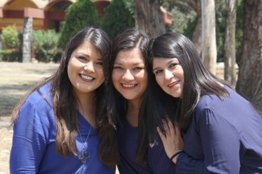 Üç profesyonel, başarılı, kendine güvenen, güçlü, düz saçlı Latin kız kardeş parkta aileleriyle vakit geçirip mutluluklarını paylaşıyorlar.