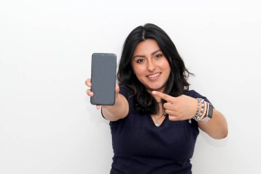 Akıllı telefonu işaret eden neşeli genç Latin kadın, beyaz bir arka planda online alışveriş uygulaması