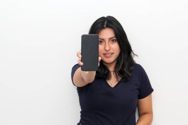 Joyful young latin woman pointing at smartphone in hand, online shopping application on a white background