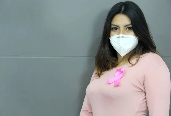 Latin woman with pink blouse and pink ribbon for campaign against breast cancer on white background