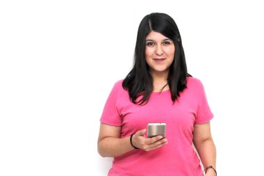 Siyah saçlı ve pembe tişörtlü genç bir kadın cep telefonundan heyecanlı bir şekilde internetten alışveriş yapıyor, mesaj gönderiyor ve alıyor.