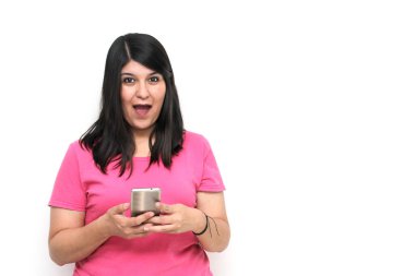 Young adult woman with black hair and pink t-shirt writes, sends and receives messages on her cell phone excitedly shopping online