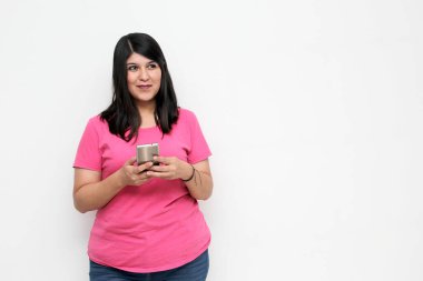 Young adult woman with black hair and pink t-shirt writes, sends and receives messages on her cell phone excitedly shopping online