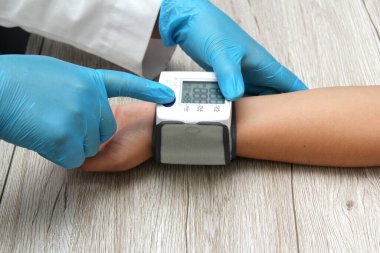Doctor use blood pressure monitor with patient to diagnose hypertension due to kidney disease, thyroid, tumor, drugs, overweight, stress, diabetes, smoking