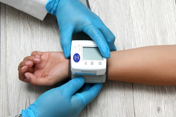 Doktor, böbrek hastalığı, tiroid, tümör, uyuşturucu, aşırı kilo, stres, şeker hastalığı ve sigara yüzünden hipertansiyon teşhisi koymak için hastayla birlikte tansiyon monitörü kullanır.