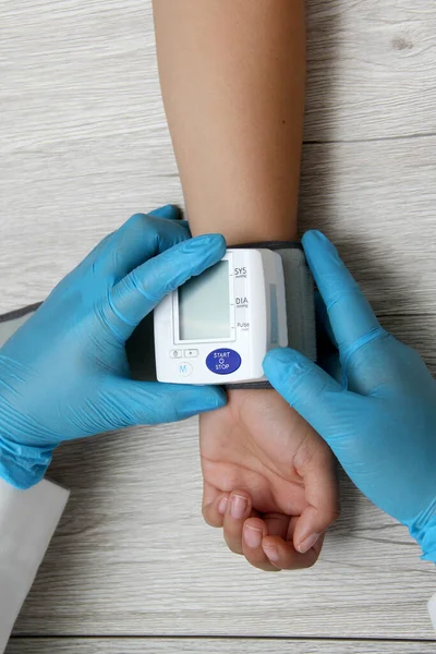 Doktor, böbrek hastalığı, tiroid, tümör, uyuşturucu, aşırı kilo, stres, şeker hastalığı ve sigara yüzünden hipertansiyon teşhisi koymak için hastayla birlikte tansiyon monitörü kullanır.