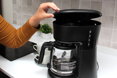 Kadınların elleri, mutfakta kahve makinesinde lezzetli ve aromatik bir kahve hazırlar. Kahvaltı için su ve taze öğütülmüş kahve.