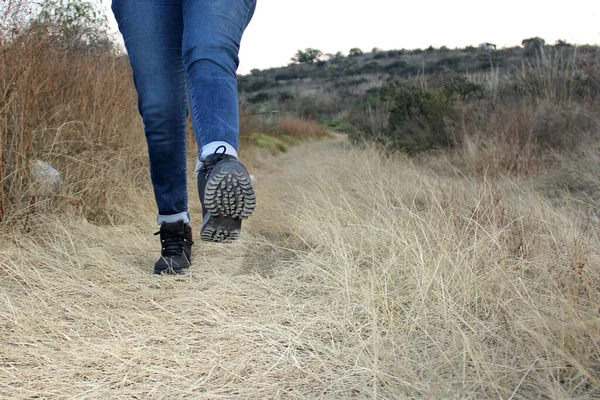 Legs with denim pants and black hiking boots in the middle of the field walk, pose, play, explore, discover and live in freedom