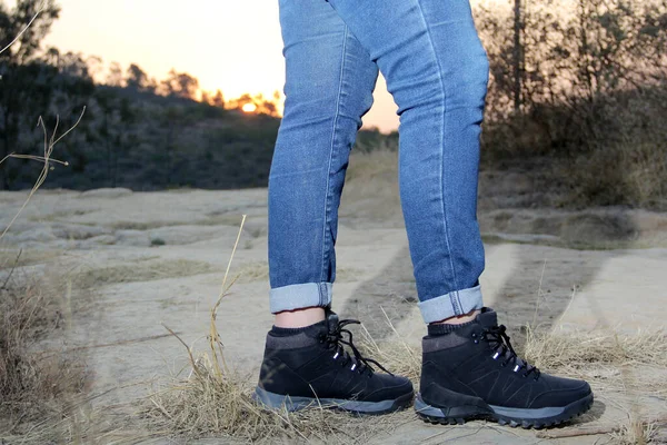 Legs with denim pants and black hiking boots in the middle of the field walk, pose, play, explore, discover and live in freedom