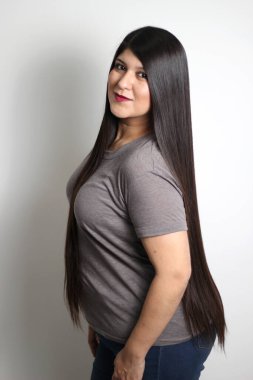 Latin genç kadın siyah saçlarının ne kadar ipeksi ve parlak olduğunu gösteriyor. Çok uzun, düz, çok mutlu ve güzel saçlarıyla gurur duyuyor.