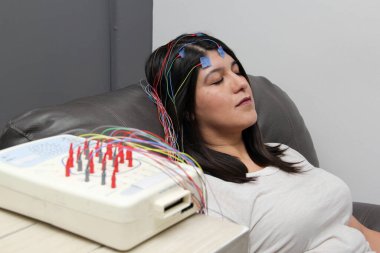 Latin yetişkin kadın nöroloji uzmanlık ofisinde bir hasta ve beynin elektriksel aktivitesini görmek için elektroensefalogram çalışması yapılıyor.