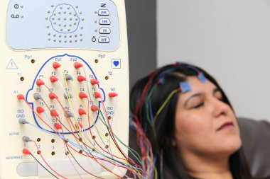 Latin yetişkin kadın nöroloji uzmanlık ofisinde bir hasta ve beynin elektriksel aktivitesini görmek için elektroensefalogram çalışması yapılıyor.