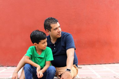 Bekar baba ve koyu renk saçlı Latin oğul birlikte oynayıp Babalar Günü 'nde ailece vakit geçirip zaferi kucaklayıp öperek kutluyorlar.