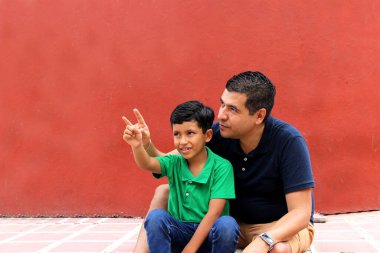 Bekar baba ve koyu renk saçlı Latin oğul birlikte oynayıp Babalar Günü 'nde ailece vakit geçirip zaferi kucaklayıp öperek kutluyorlar.