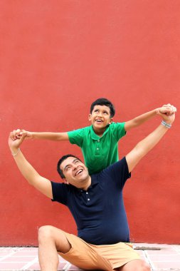 Bekar baba ve koyu renk saçlı Latin oğul birlikte oynayıp Babalar Günü 'nde ailece vakit geçirip zaferi kucaklayıp öperek kutluyorlar.