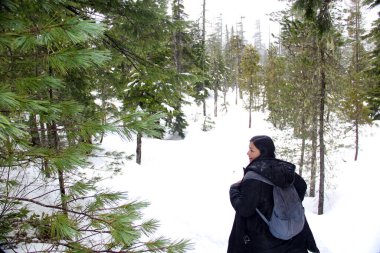 Siyah ceketli ve gri sırt çantalı Latin yetişkin kadın karlı dağda yürüyüş yapıyor. Çok mutlu, özgür, dolu, pozitif, hayatı ve sporu seviyor.