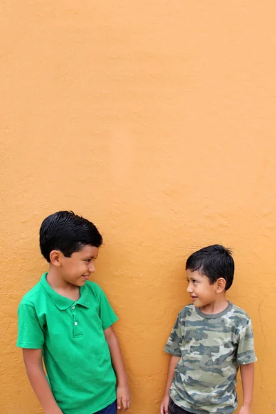 Dvě Tmavovlasé Latinskoamerické Děti Stojící Před Žlutou Zdí Žijí Chudobě — Stock fotografie