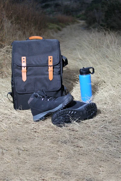 Backpack, thermos and boots for hiking in the mountains at sunrise, equipment for extreme outdoor sport