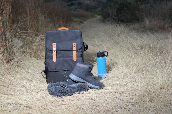 Backpack, thermos and boots for hiking in the mountains at sunrise, equipment for extreme outdoor sport