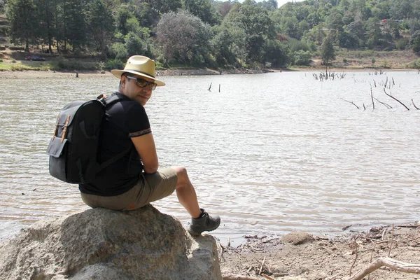 Latin Adult Man Hat Sunglasses Sitting Stone Next Lake Makes — Stock Photo, Image